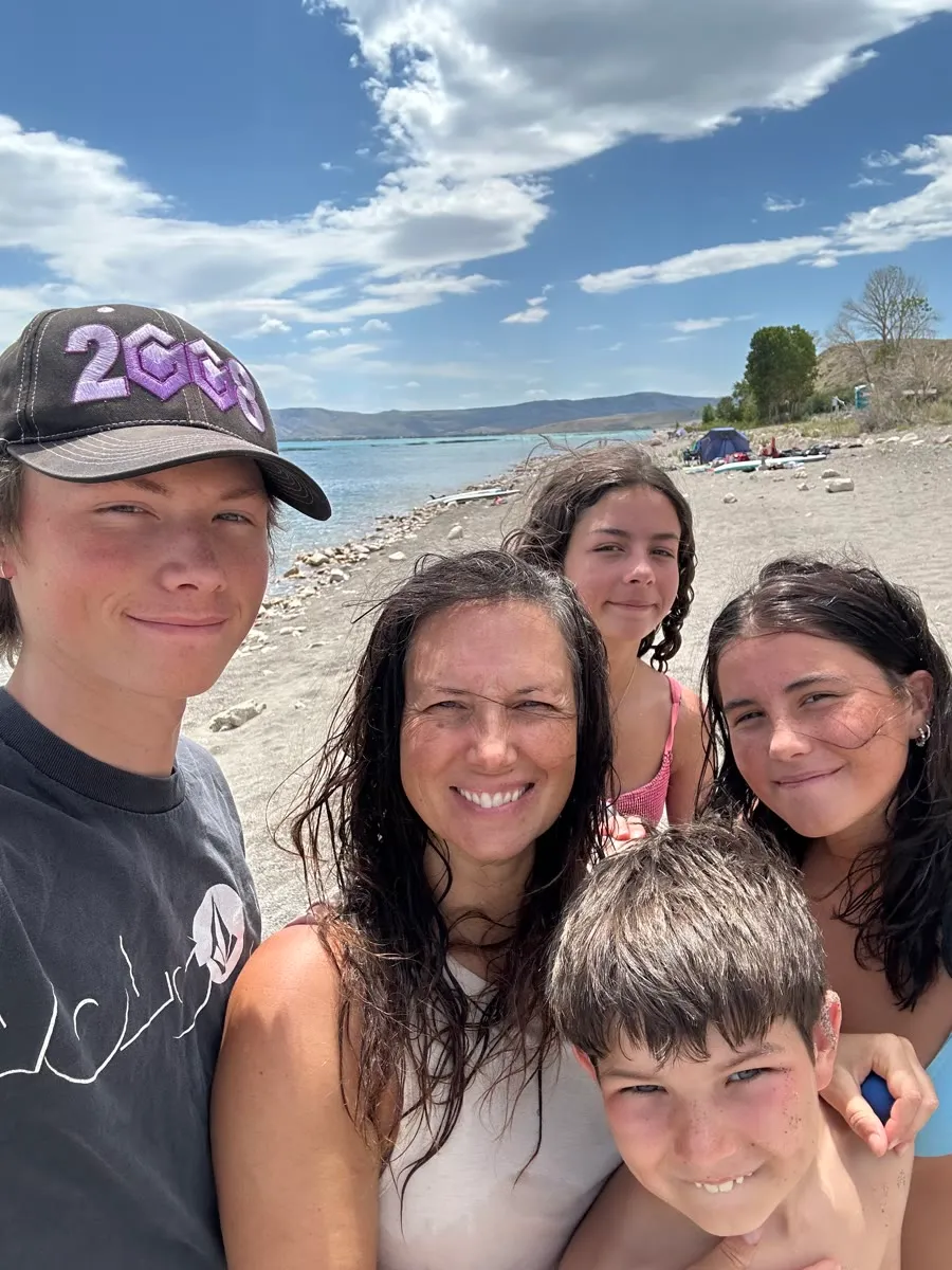 Vanessa with her four children on a beach, a lake and blue sky behind them.