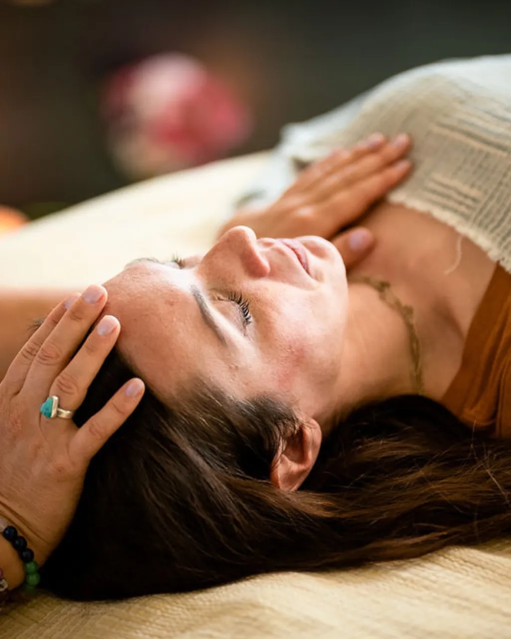 Vanessa cradling a resting client's head and temple with her hands during a hands-on somatic session.