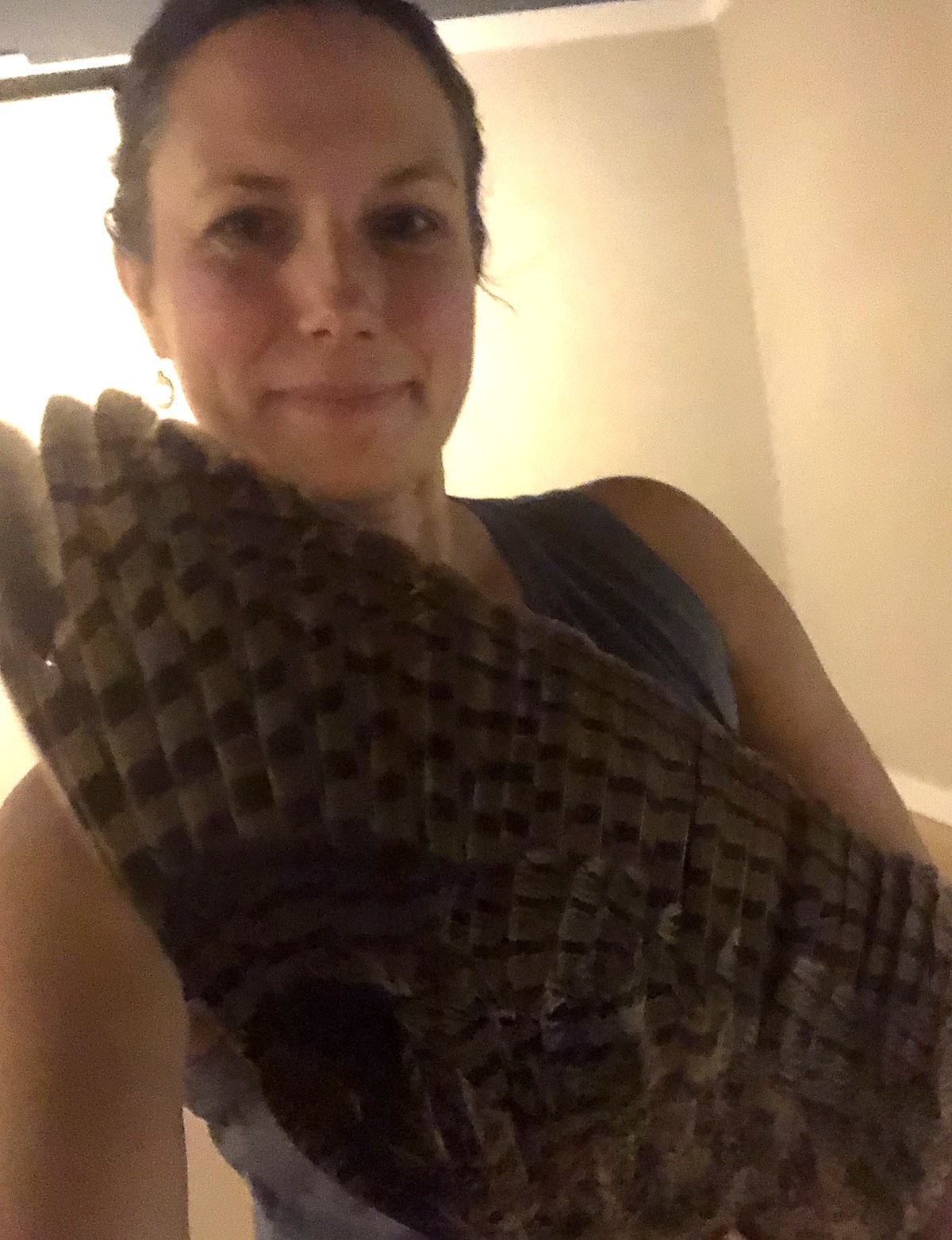 Vanessa holding a large barred owl wing against her chest and smiling softly, indoors in 2019.